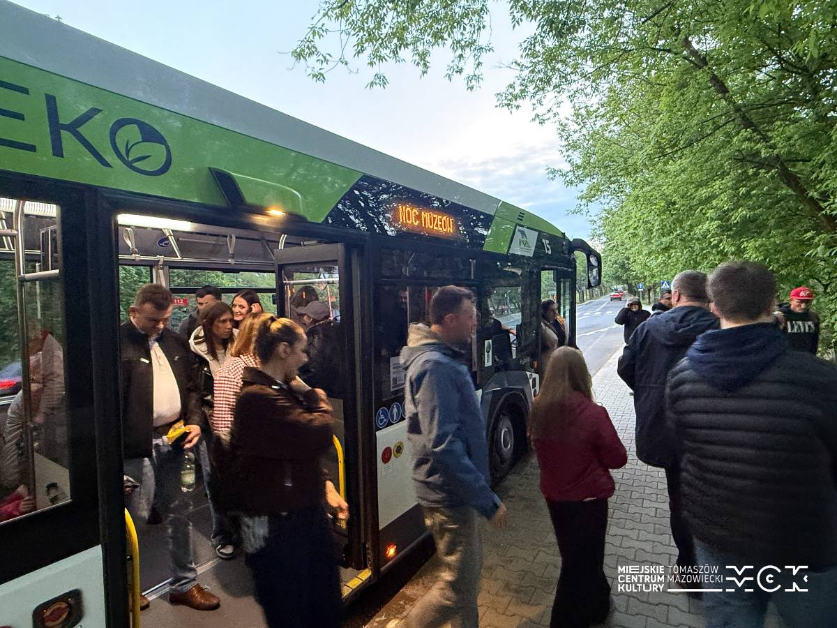 Na zdjęciu ludzie wysiadający z autobusu obsługującego bezpłatna linie MZK podczas Nocy Muzeów 2026. Autokar w kolorach biało-zielonym, hybryda, na wyświetlaczu z nazwa kursu napis Noc Muzeów