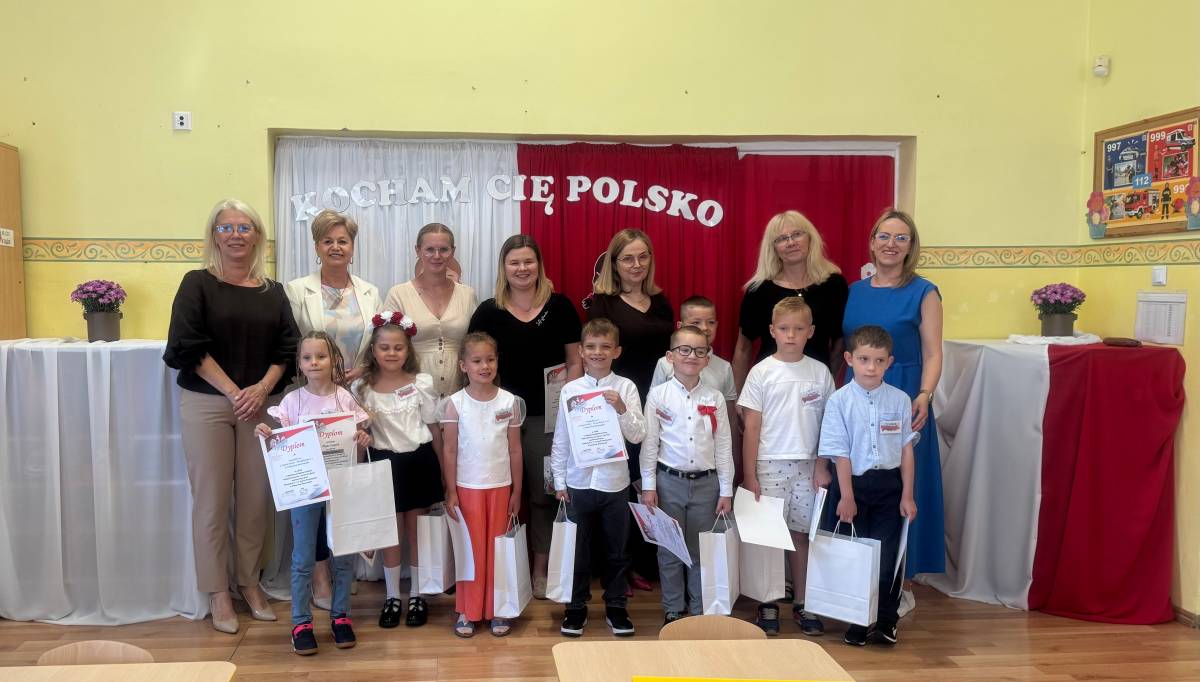 Przedszkolaki przy stolikach podczas wykonywania zadań postawionych przed nimi w konkursie patriotycznym Kocham Cię Polsko