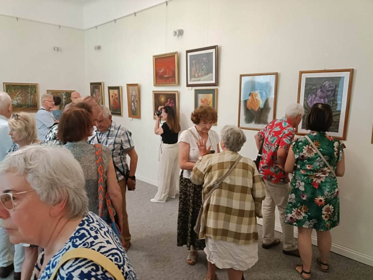 Na zdjęciu oglądający wystawę pt. Kredka i pędzlem. Obrazy wiszą na ścianach w sali wystawienniczej muzeum