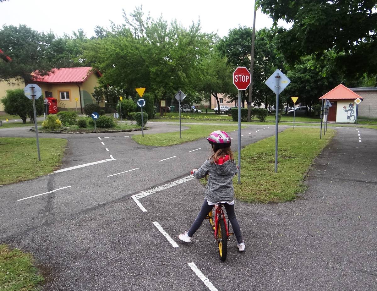 Na zdjęciu dziewczynka w kasku na rowerku podczas jazdy na edukacyjnej ścieżce rowerowej