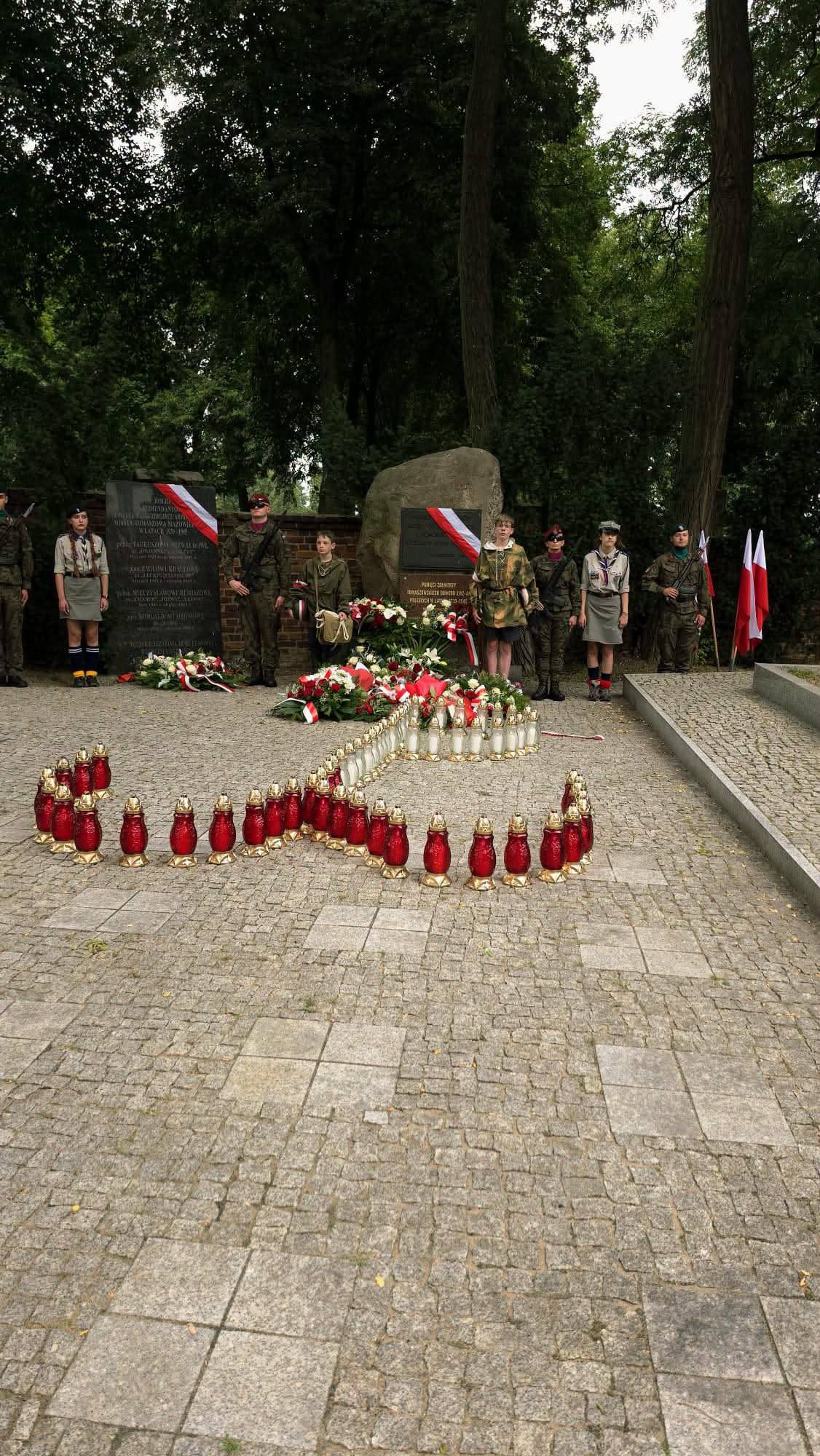 Na zdjęciu warty honorowe w mundurach historycznych pełnione przy Miejscach pamięci Narodowej na Cmentarzu Wojennym przy ul. Smutnej. Kwiaty złożóne przed obeliskami, biało-czerwone flagi oraz znak Polski Walczącej ułożony z biało-czerwonych zniczy