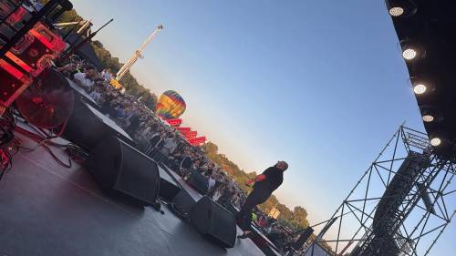 Nocna Jazda 2026, jeden z koncertów, artysta na scenie na Tomaszowskich Błoniach, pod scena tłum widzów, w tle obiekty wesołego miasteczka