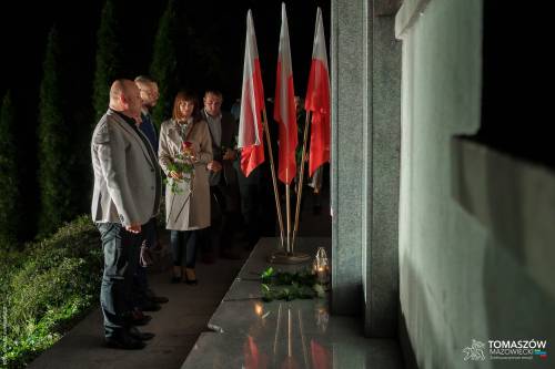 Przedstawiciele: władz miejskich, powiatowych oraz radni miejscy stoją w zadumie przed Pomnikiem Ku Czci Rozstrzelanych Członków Ruchu Oporu i Zakładników w latach 1939–1945 przy ul. Browarnej. Część z nich trzyma w dłoniach symboliczną różę.