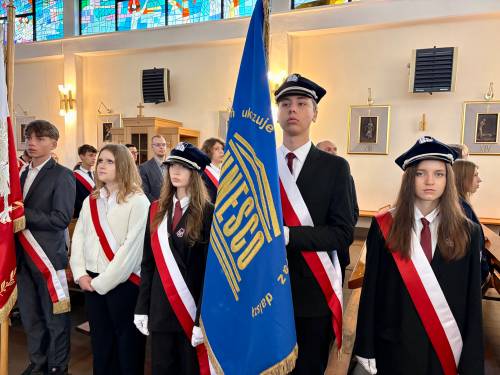 Poczty sztandarowe w kościele pw. NMP Królowej Polski przy ul. Słowackiego. Na pierwszym miejscu chorąży trzyma niebieski sztandar ze złotymi zdobieniami oraz napisem UNESCO. Obok stoją dziewczęta w galowych strojach i biało-czerwonych szarfach